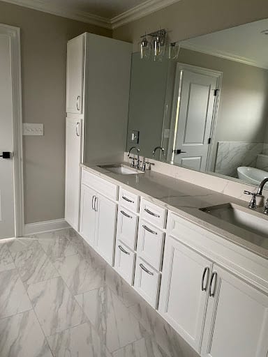 White double vanity with marble floors and large mirror in remodeled bathroom