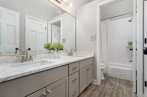 Double sink gray vanity with marble countertop and wood-look tile floor