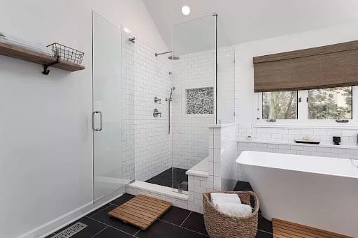 Walk-in glass shower with white subway tile and freestanding soaking tub